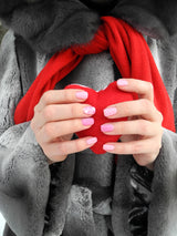 Manos de mujer agarrando un corazon. Manicura en tonos rosas y con detalles de corazones. Manicura de San Valentin